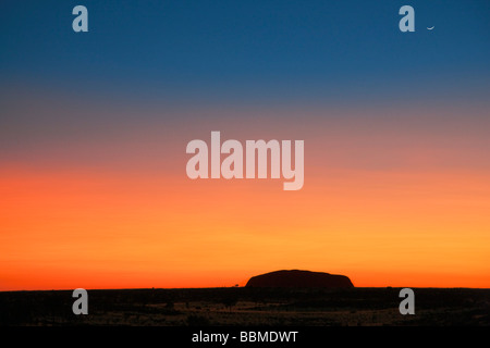 Australia, Northern Territory. Before sunrise, Uluru or Ayres Rock is silhouetted against a magnificent blood red or orange sky Stock Photo