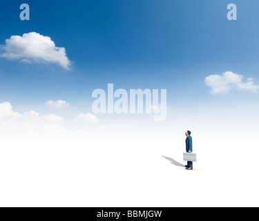 Figurine of businessman holding briefcase and looking at cloud (Digital Composite) Stock Photo