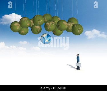 Figurine of businessman holding briefcase and looking at globe (Digital Composite) Stock Photo