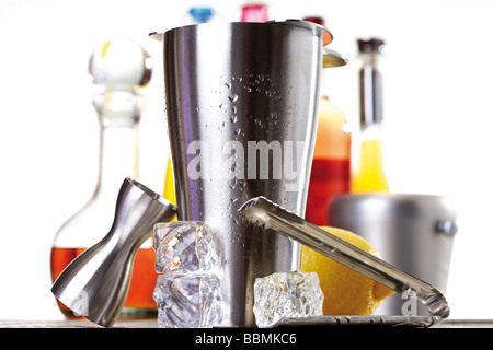 Shaker, bar equipment, ice cubes, ice tongs, measuring cup, bottles Stock Photo