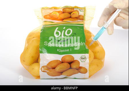 Syringe into potatoes with organic labeling on the label, symbolic picture, fraud with food with the BIO label Stock Photo