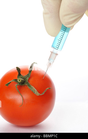 Syringe in tomato, symbolic picture, genetically modified foods Stock Photo