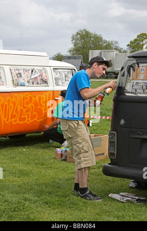 Black VW camper van being sprayed with graffiti Stock Photo