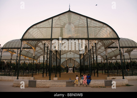 An Indian family sit under the Crystal Palace in the Lalbagh Botanical Garden of Bangalore, India. Stock Photo