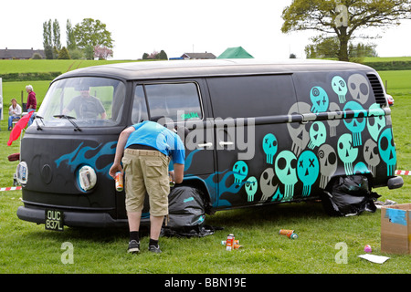 Black VW camper van being sprayed with graffiti Stock Photo