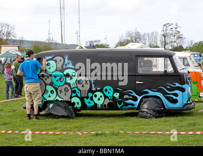 Black VW camper van being sprayed with graffiti Stock Photo