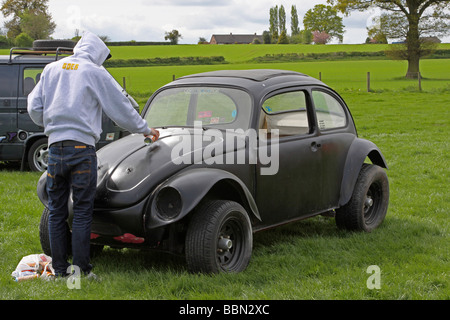 Black VW Beetle being sprayed with graffiti Stock Photo