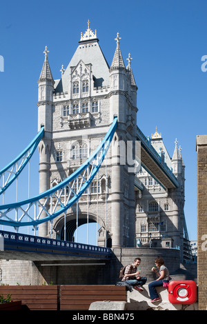Young couple sitting by Tower Bridge. London, England, UK Stock Photo