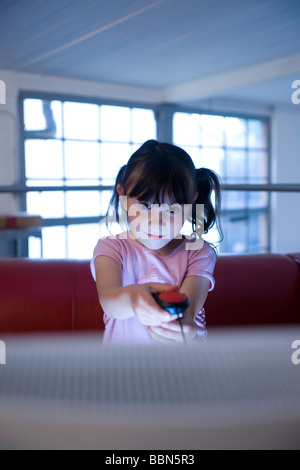 A little girl secretly playing a video game Stock Photo