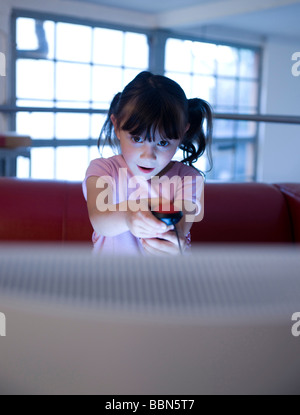 A little girl secretly playing a video game Stock Photo