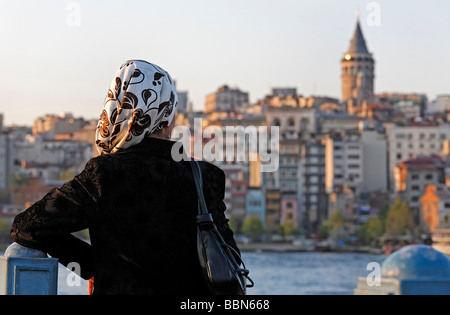 Young Muslim women with headscarf looks on the panorma of Beyoglu with the Galata Tower, Eminoenue, Istanbul, Turkey