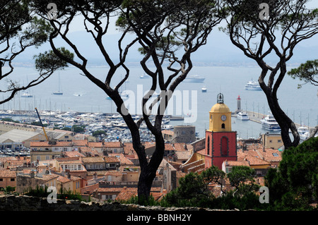 View of the clocktower, the roofs, and the bay of Saint Tropez framed by pine trees; in the French riviera, southern France Stock Photo