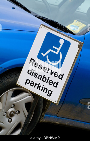 Reserved Disabled Parking sign next to blue car in car park