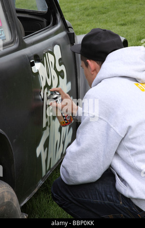 Black VW Beetle being sprayed with graffiti Stock Photo