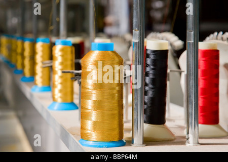 Long row of colored fabric spools in manufacture Stock Photo