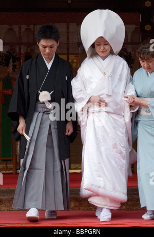 Bride and groom wearing traditional kimono leaving Shinto shrine after wedding ceremony Stock Photo