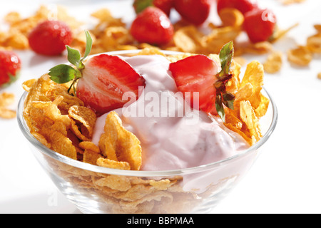 Cornflakes with strawberries and yogurt in a glass bowl Stock Photo