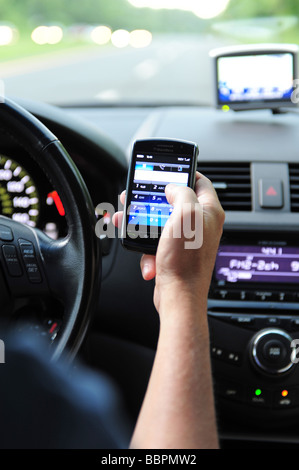 Man using a blackberry cell phone to make a calll while drive his car Stock Photo