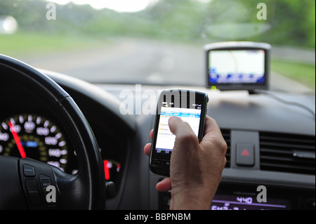 Man using a blackberry cell phone to check email while drive his car Stock Photo