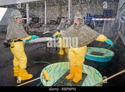 A volunteer in chemical biological prorective clothing is decontaminated by a colleague with a water spray Stock Photo