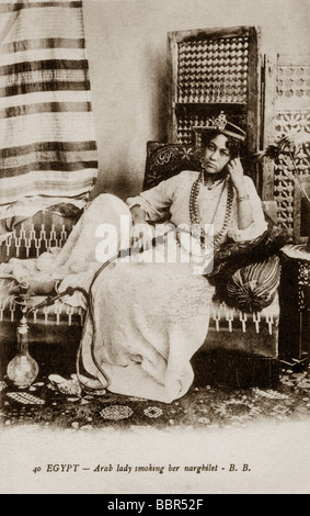 Early 1900's postcard of Egyptian lady reclining smoking her narghile Stock Photo