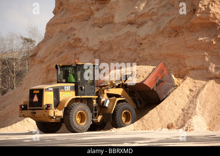 Caterpillar front loader loading sawdust from a big inventory pile , Finland Stock Photo