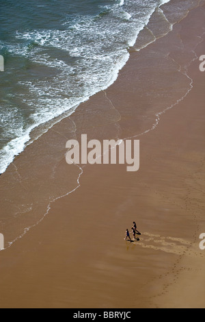 Three People walking on Beach Stock Photo