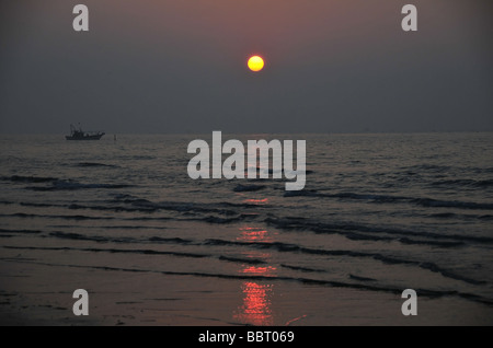 Red sunrise over a beach view of a lobster pot fishing boat on a calm Adriatic Sea at Lido di Jesolo, Northern Italy Stock Photo
