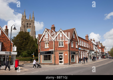 St Mildred's Parish Church clock tower behind shops on High Street in historic Wealden town. Tenterden Kent England UK Britain Stock Photo