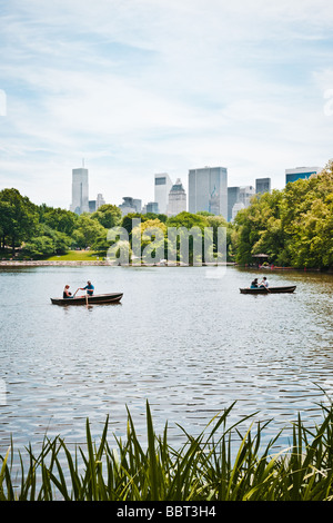 Couples rowing in rented row boats in a lake in Central Park against the Manhattan skyling in the background on a summer day. Stock Photo