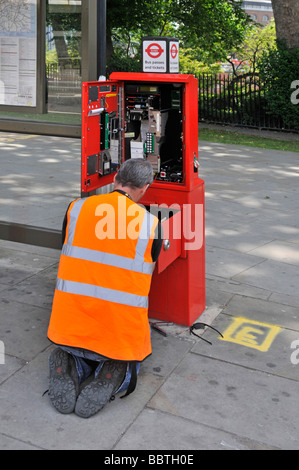 Engineer technician attending to ticket purchase machine beside bus stop logo on back of jacket removed Stock Photo
