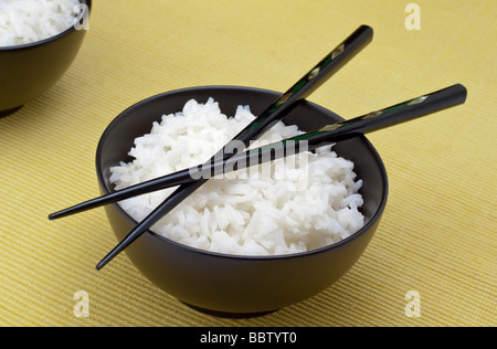 White rice in a black dish with two chopsticks Stock Photo