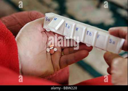 Close up of pensioner taking her daily selection of medicine from a weekly dispenser UK Stock Photo