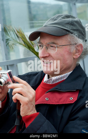 man on his sixties taking a picture with a compact camera Stock Photo