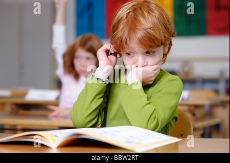 Children in primary school, boy daydreaming or looking unsure, thoughtful, sad or frustrated, boys becoming the losers or failu Stock Photo