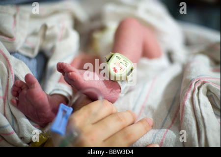 Newborn boy's leg fitted with 'baby lojak', a sensor which will sound if the baby leaves a secure area Stock Photo