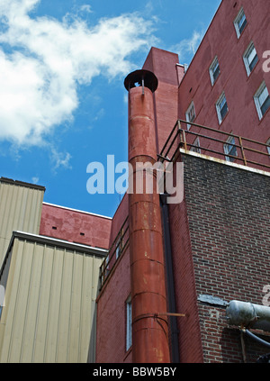 commercial tall buildings with smokestack chimney and air conditioning equipment, brick against clouds in sky Stock Photo