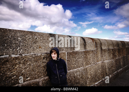 teenager leaning against a wall Stock Photo