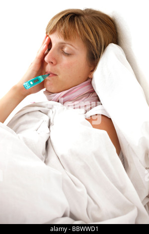 Woman at home, ill with fever in her bed, uses a clinical thermometer for measuring body temperature. Stock Photo