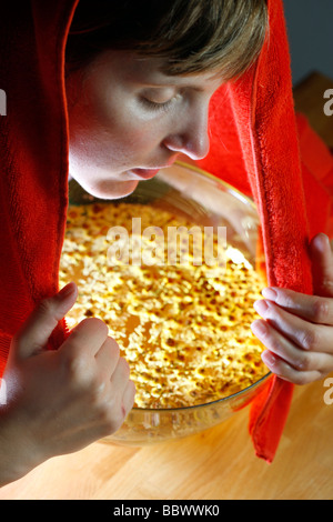 Woman inhaling the fumes of a camomile infusion against a cold. Stock Photo