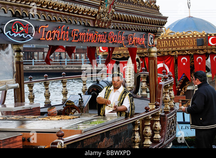 Turk in traditional costume preparing fish sandwiches on a historically decorated boat, Golden Horn, Eminoenue, Istanbul, Turkey Stock Photo