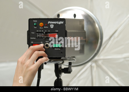 Turning on a professional photo studio light with umbrella attached. Stock Photo