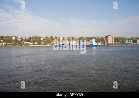 A small to medium size container ship heads out to see along the Elbe, Hamburg Stock Photo