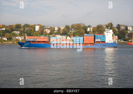 A small to medium size container ship heads out to see along the Elbe, Hamburg Stock Photo