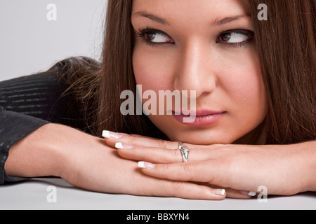 Young woman resting chin on hands and looking sideways Stock Photo