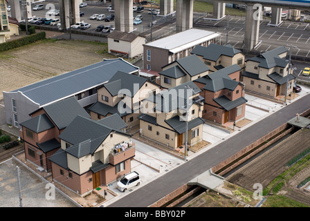 Eight residential homes squeezed into a small plot of land beside an elevated freeway without any greenery in Japan Stock Photo