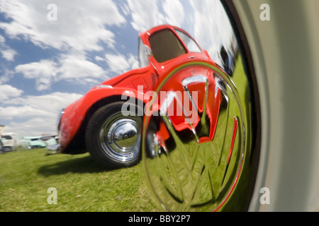 Orange Volkswagen Beetle reflected in chrome VW hub cap Stock Photo