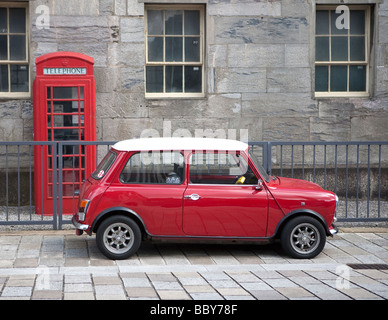 red Austin Cooper mini car parked in front of red telephone box. Royal William Yard, Plymouth, Devon, England, UK Stock Photo
