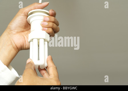 Woman's hands changing energy saving light bulb Stock Photo