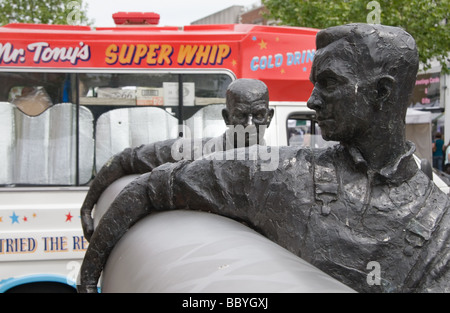 Sculpture of two men carrying a roll of lino, with an ice cream van in the background: Staines, Middlesex. Stock Photo